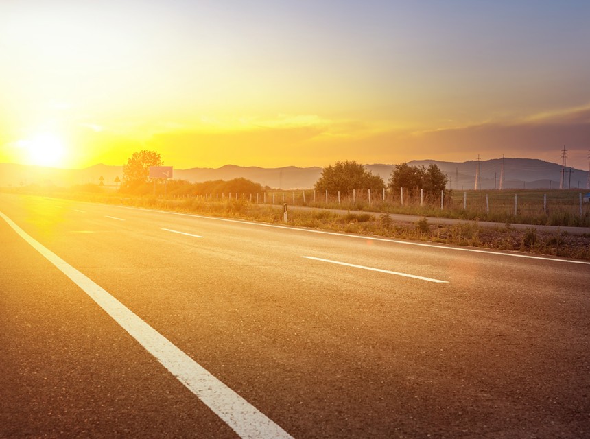 A sunset over a rural road near the mountains.